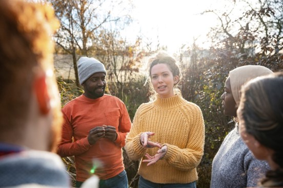 vulnerable-workers-header woman in yellow jumper and man in red jumper talking to group of people outside
